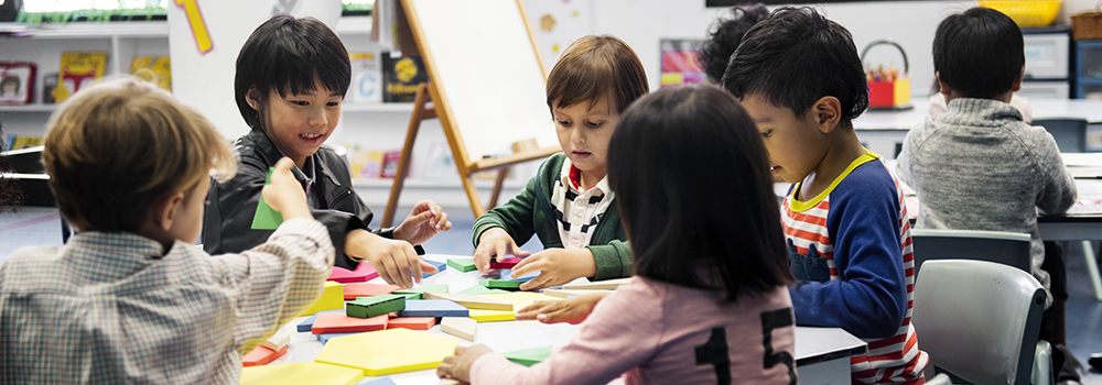 Kindergarten students from the 80s at a craft table.