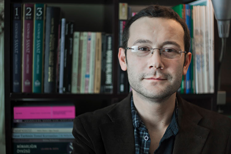 A young professional standing in front of a bookcase