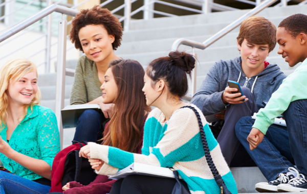 Image of diverse group of young adults sitting on front steps of an academic building.