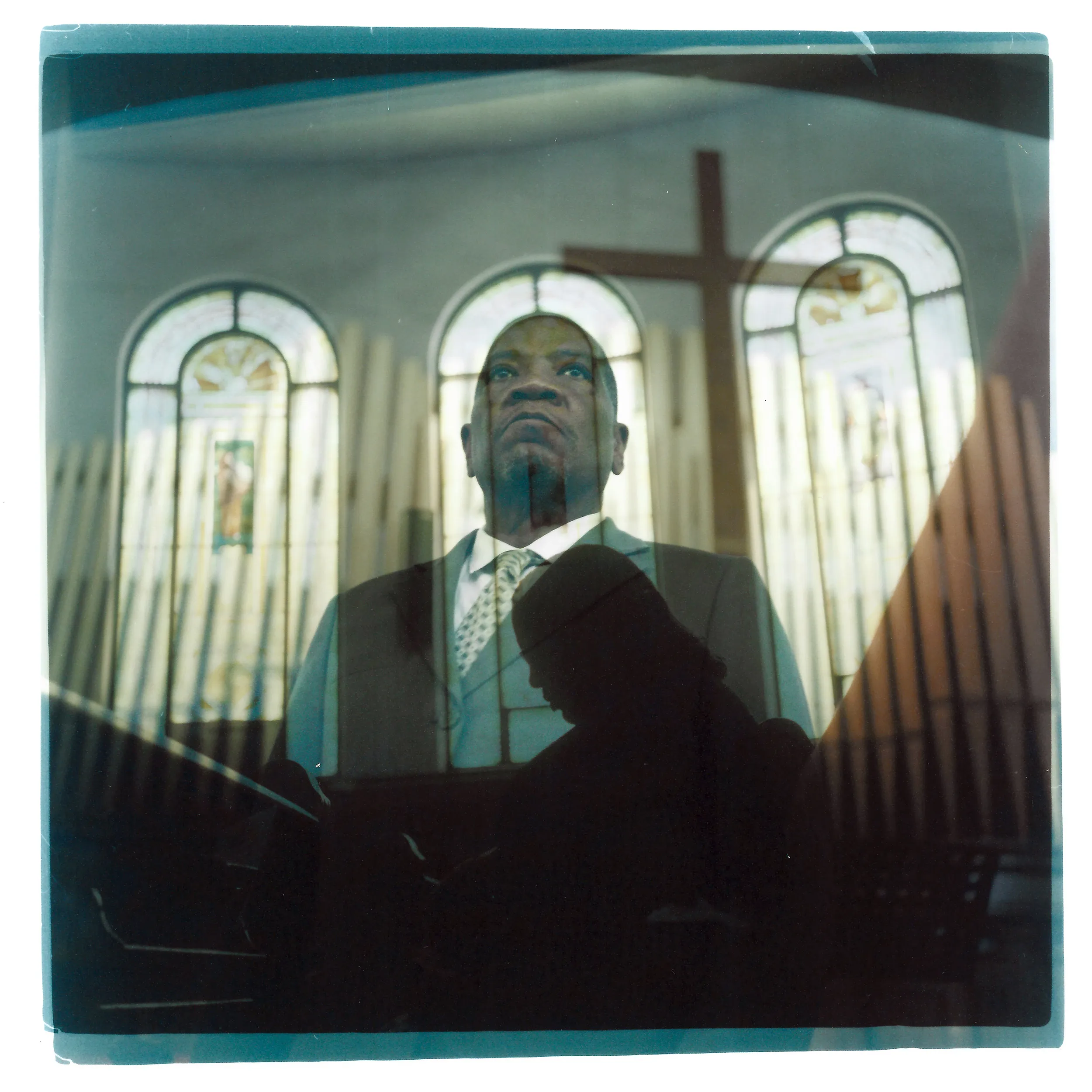 A double exposure made from a headshot of Rev. Jimmie Hardaway Jr. layered with a photo of a parishioner bowing her head in prayer.