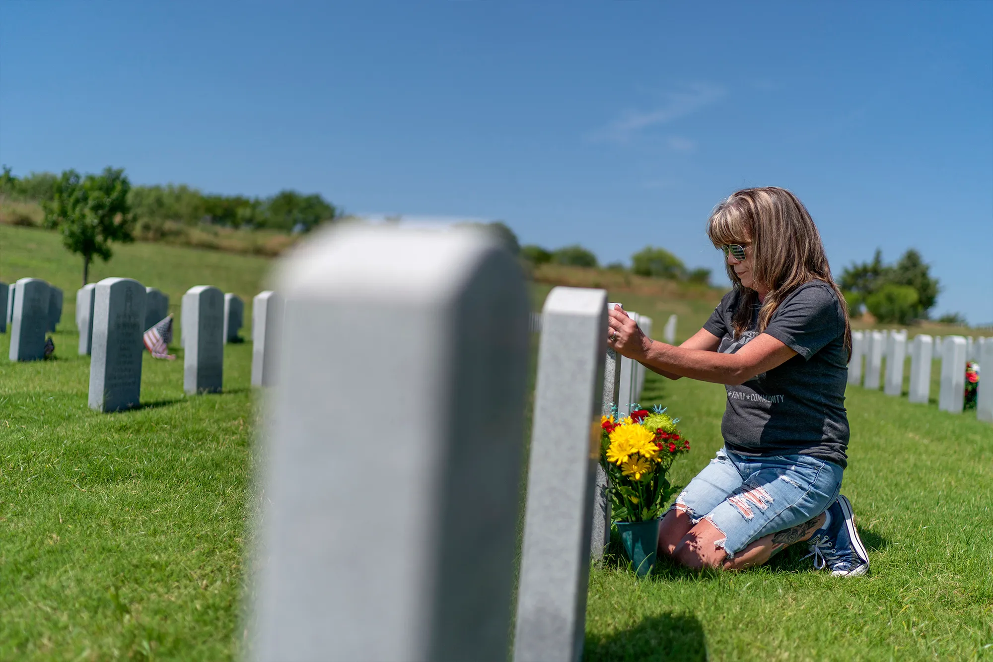 Barbie Rohde kneeling down touching her sons tombstone. 
