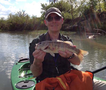 Angler in kayak holding guadalupe bass