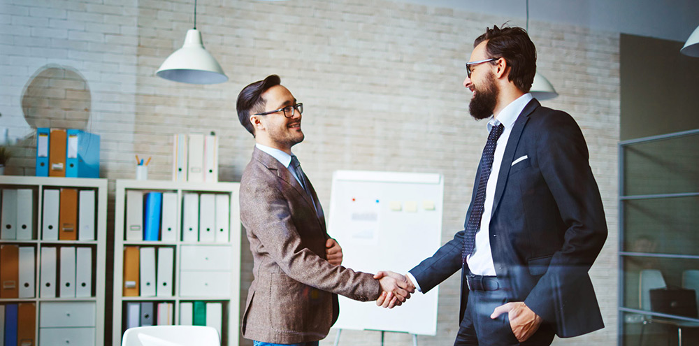 Two men shaking hands, developing a partnership.