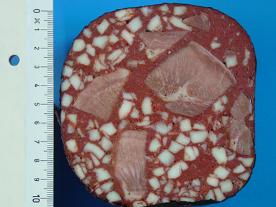 Zungenwurst: Das Foto zeigt eine Scheibe einer Zungenwurst. In einer feinkörnigen roten Masse sind würfelförmige, etwa erbsengroße Speckstückchen sowie bis etwa walnussgroße, gegarte Zungenstücke eingebettet.