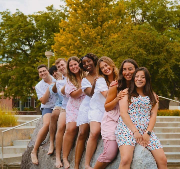 Eight Huskers sit in a row on a rock in Broyhill Fountain.